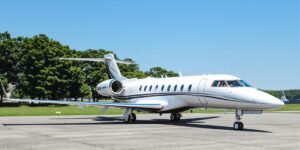 Medium-sized private jet on a tarmac with blue sky.